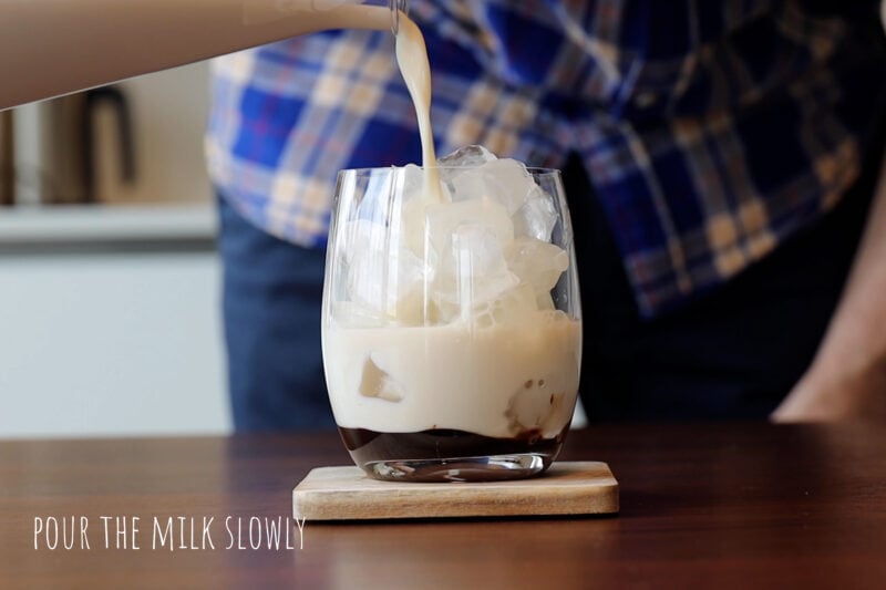 Pouring the milk into the coffee glass.